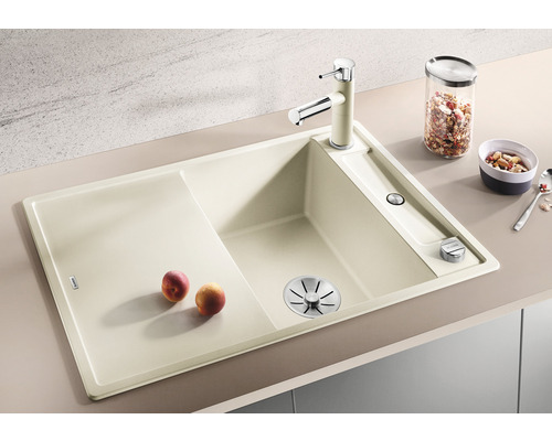 Beige keuken spoelbak met afdruiprek, kraan en zeepdispenser.