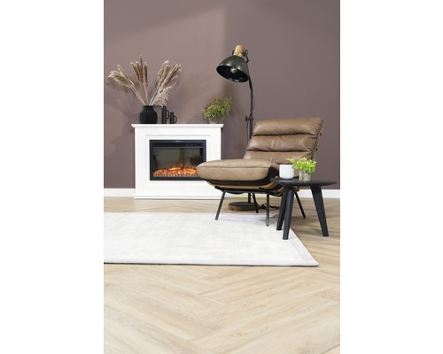 Woonkamer met fauteuil, vloerlamp, open haard en tapijt op houten vloer