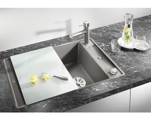 Keukenspoelbak met kraan, snijplank, mes en stervrucht op een aanrecht.