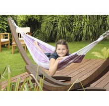 Meisje ontspant in een gestreepte hangmat met houten frame in de tuin