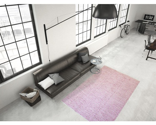 Overzicht van een kamer met een bank, vloerkleed en grote ramen