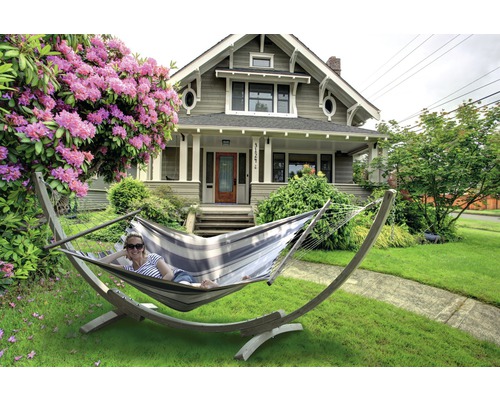 Vrouw ontspant in een hangmat in de tuin voor een woonhuis.
