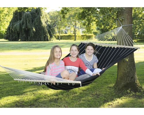 Drie kinderen zitten in een hangmat die tussen twee bomen is opgehangen.