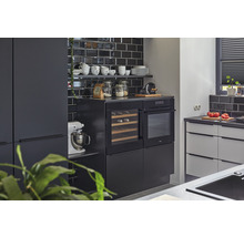 Moderne keuken met zwarte tegels, inbouwapparatuur en keukengerei op planken.