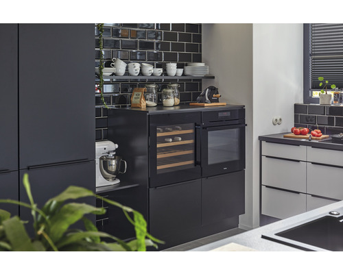 Moderne keuken met zwarte tegels, inbouwapparatuur en keukengerei op planken.