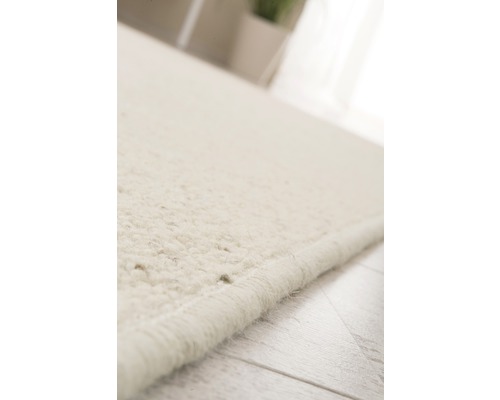 Detailopname van een lichtgekleurd vloerkleed met pool op een houten vloer.