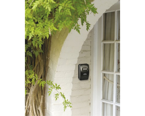 Sleutelkluis met cijfercode aan een huismuur naast een deur