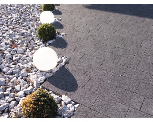 Tuinpad bestraat met betontegels, gedecoreerd met grind, bolvormige lampen en buxusbollen