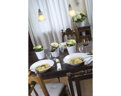 Gedekte eettafel met pasta, bloemen en wijn onder hanglampen