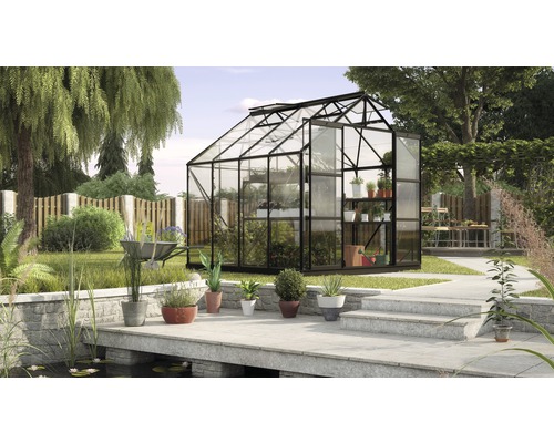 Kas in tuin met planten, tuinvijver en stenen pad