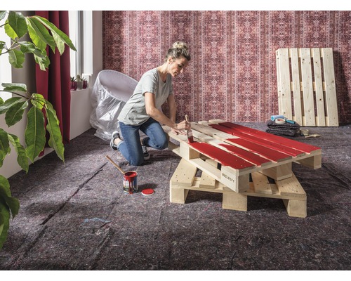 Vrouw schildert houten pallet met verf voor een doe-het-zelf project