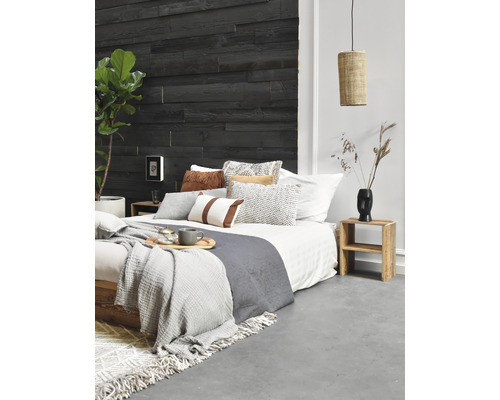 Slaapkamer met houten wand, bed, kussens, dekens, bijzettafel en lamp