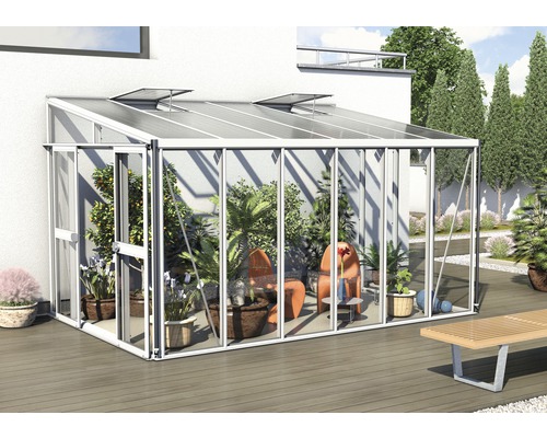 Kas met planten en tuinmeubelen op een terras