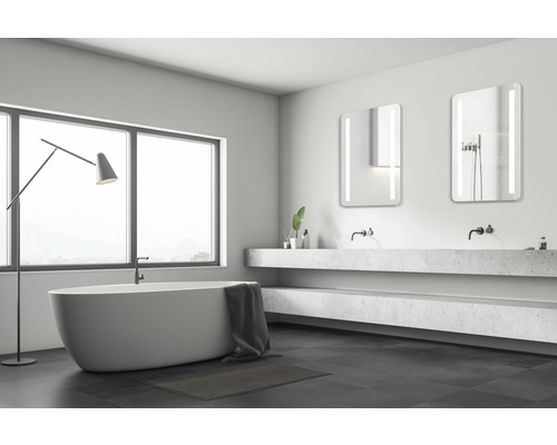 Lichte badkamer met ligbad, wastafel en spiegels