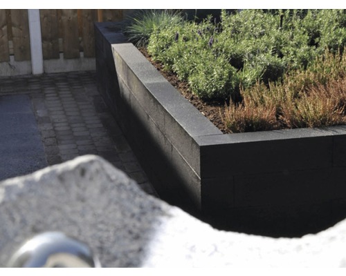 Verhoogde stenen plantenbak met beplanting in de tuin.