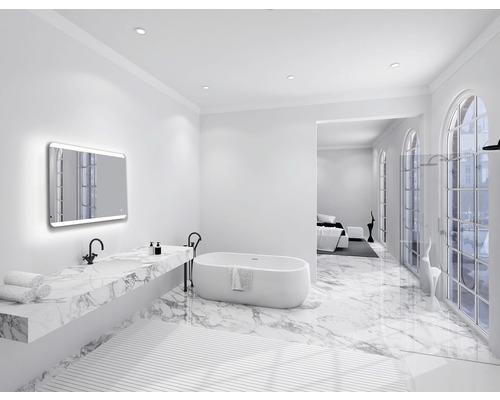 Lichte badkamer met ligbad, wastafel met marmeren blad en verlichte spiegel