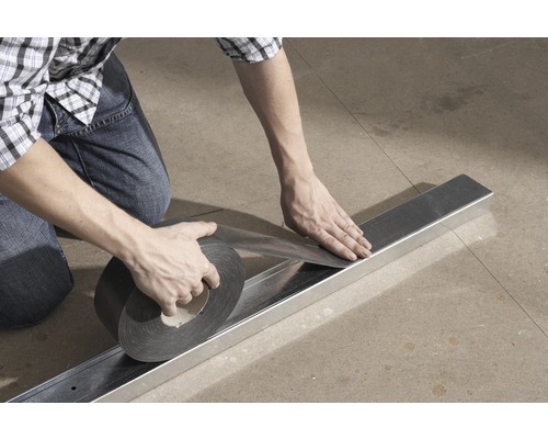 Een persoon bevestigt afdichtingstape aan een metalen profiel.