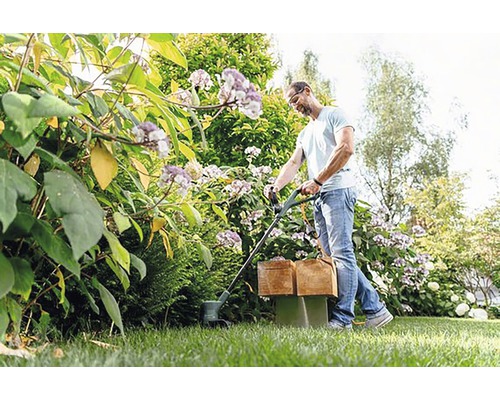 Man gebruikt een gazonrandtrimmer in de tuin.