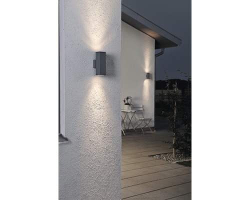 Twee grijze buitenwandlampen verlichten een muur van een huis.