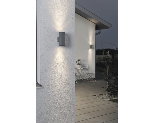 Twee grijze wandlampen verlichten een buitenmuur van een huis