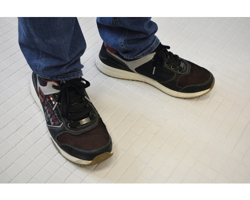 Een paar veterschoenen van textiel en synthetisch materiaal aan de voet van een persoon.