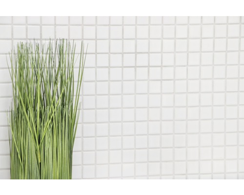 Decoratieve groene kunstplant voor een wand met witte vierkante tegels
