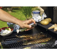 Iemand besproeit vis op een barbecue met olie.