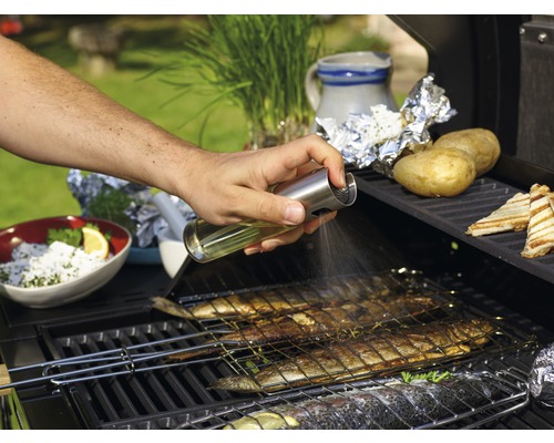 Iemand besproeit vis op een barbecue met olie.
