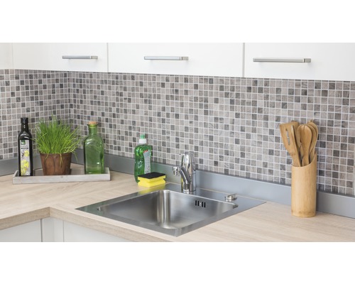 Roestvrijstalen spoelbak met kraan op een aanrecht in een lichte keuken met mozaïektegels