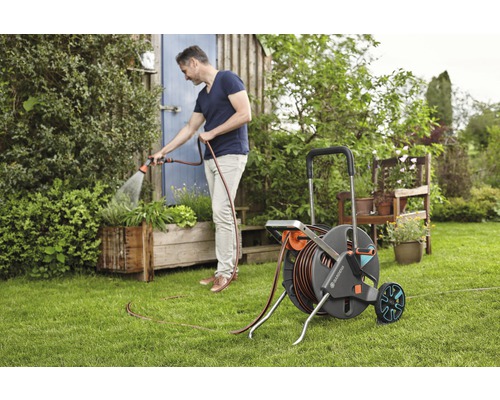 Man besproeit planten met een tuinslanghaspel in de tuin.