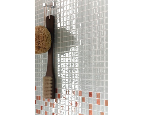 Gedetailleerde opname van een wand met mozaïektegels, een badspons en een borstel