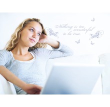 Vrouw met laptop op de bank voor muursticker met vlinders en spreuk