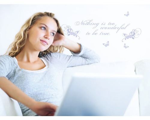 Vrouw met laptop op de bank voor muursticker met vlinders en spreuk
