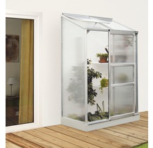 Aangebouwde kas met planten naast een raam op een houten terras