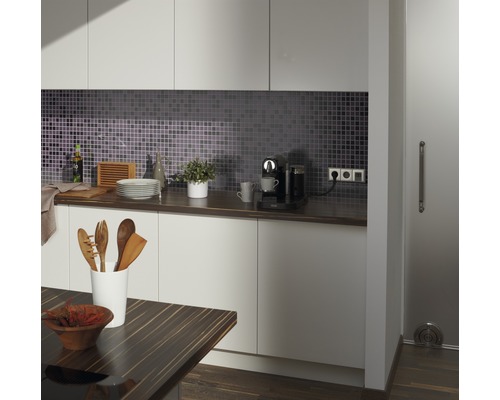 Moderne keuken met mozaïektegels, werkblad, keukengerei en koffiezetapparaat.