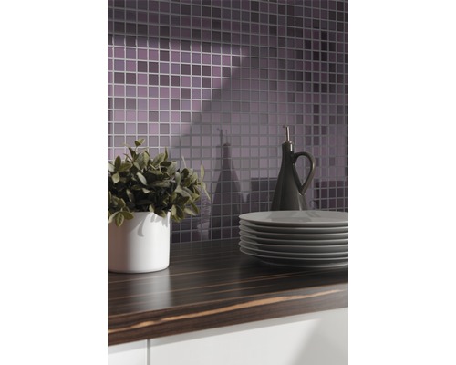 Keukenscène met mozaïektegels, werkblad, servies, plant en oliefles