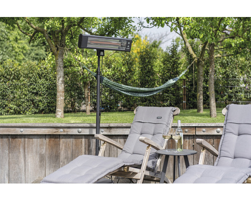 Terrasscène met terrasverwarmer op statief en ligstoelen in de tuin.