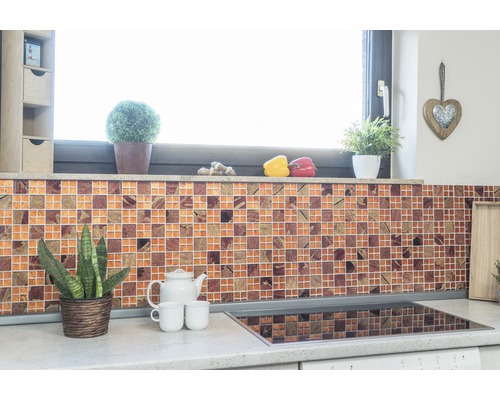 Keukenscène met mozaïektegelwand, planten en keukengerei op het aanrecht.