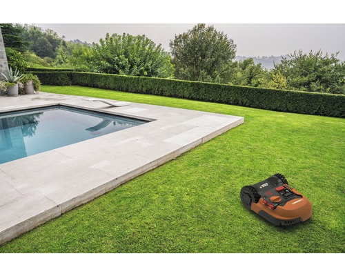 Robot grasmaaier op gazon naast een zwembad