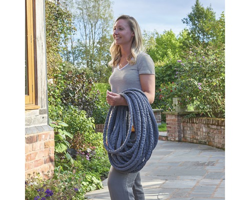 Vrouw draagt flexibele tuinslang van textielweefsel in de tuin