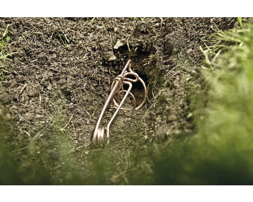 Een draadklem ligt in een gat in de grond.