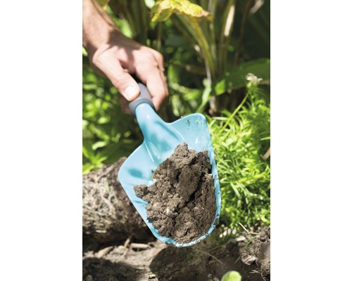 Een handtuinschep met aarde in de tuin.