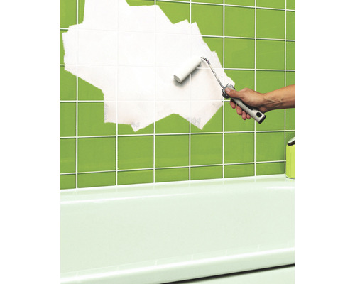 Iemand schildert tegels in de badkamer met een verfroller.