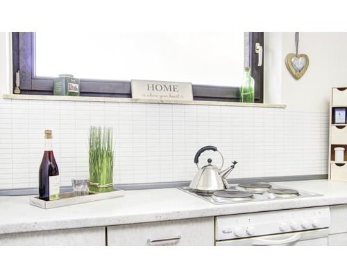 Keukenscène met kookplaat, waterkoker, fles, glas en decoratieve elementen.