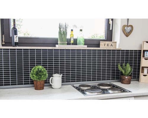 Keukenscène met zwarte tegels, kookplaat, ramen en decoraties.