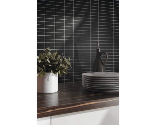 Keukenscène met zwarte wandtegels, houten werkblad, servies en decoratie