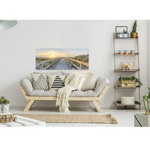 Woonkamer met bank, rek en een muurschildering van een pad naar het strand bij zonsondergang