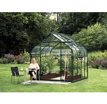 Tuinkas met planten en vrouw aan een tafel in de tuin