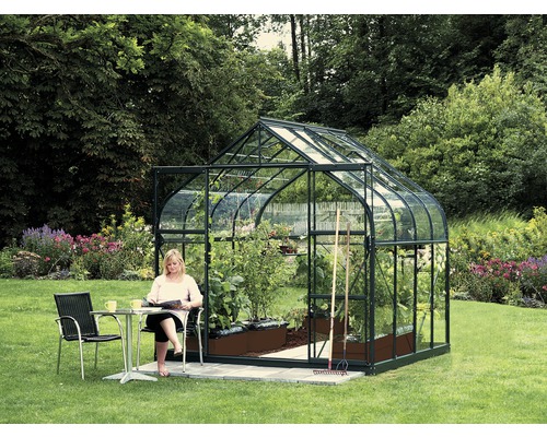 VITAVIA Kweekkas Diana 6700 groen met enkel veiligheidsglas 3 mm 264 x 258 cm Tuinkas met planten en vrouw aan een tafel in de tuin
