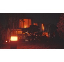 Verlichte tuin met modern huis op de achtergrond.